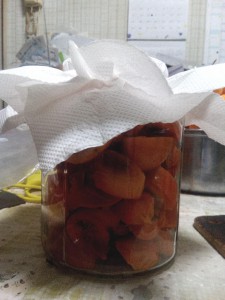 ガラス瓶に柿を切って入れてあり、クッキングペーパでふたをしている